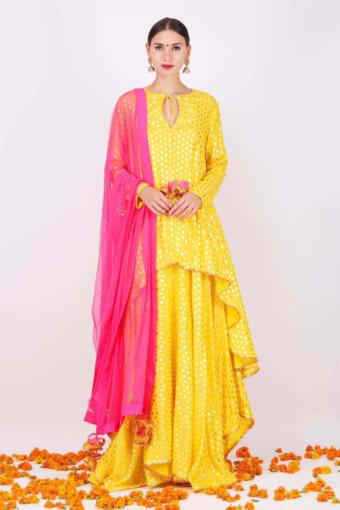 Yellow crepe foil printed asymmetrical tunic with yellow crepe foil printed asymmetrical skirt and fuschia pink net embroidered dupatta.