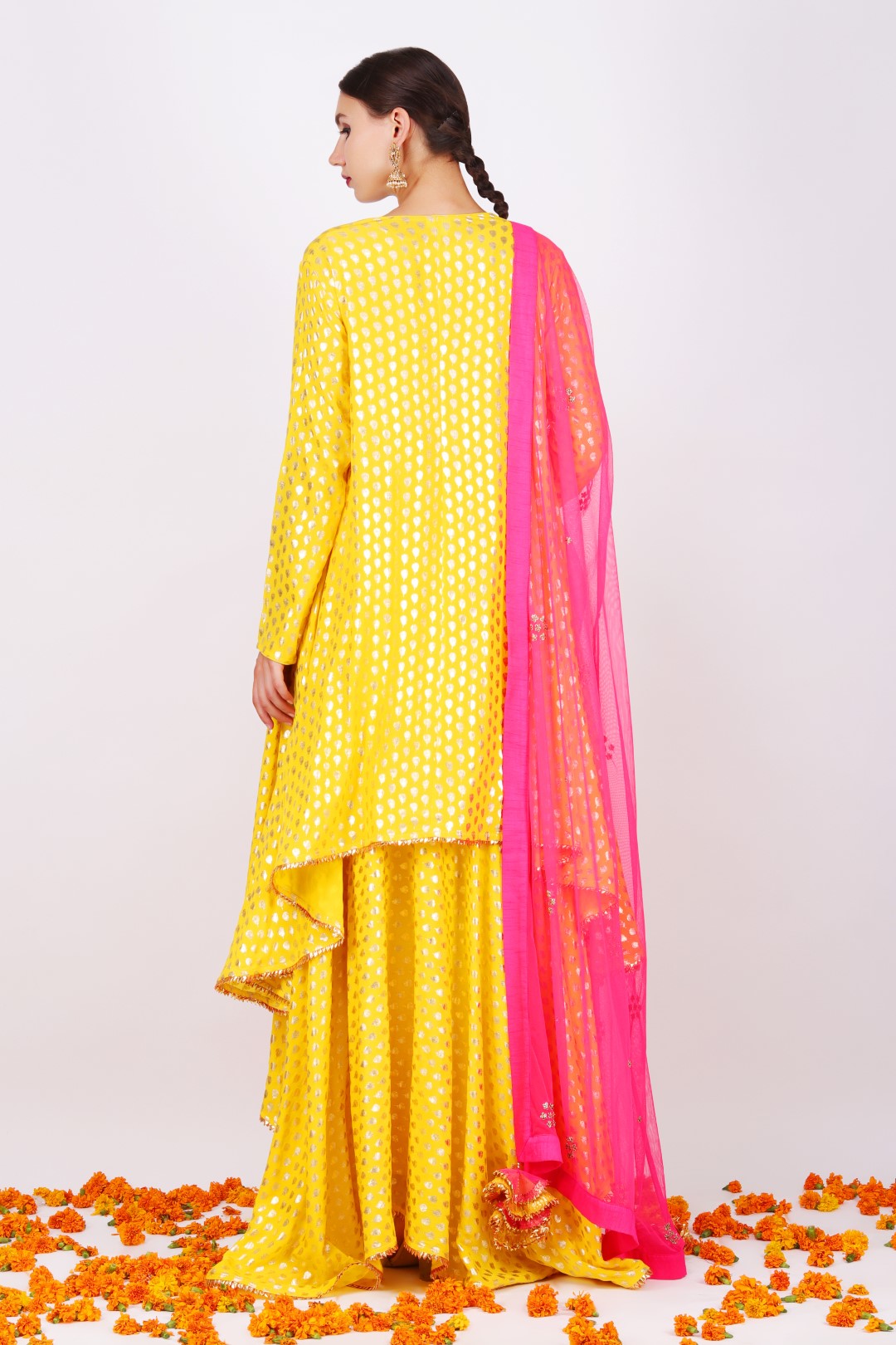 Yellow crepe foil printed asymmetrical tunic with yellow crepe foil printed asymmetrical skirt and fuschia pink net embroidered dupatta.