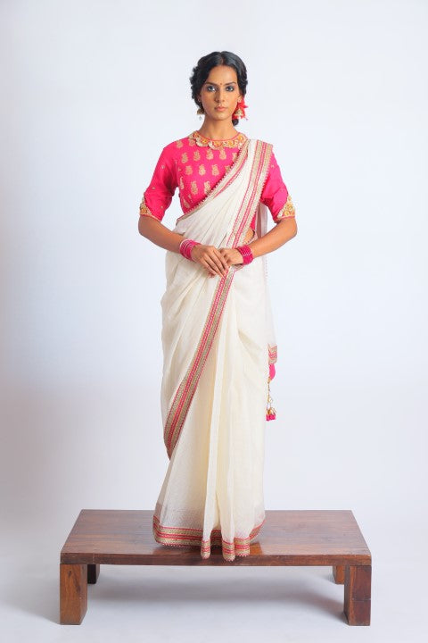 IVORY HANDWOVEN KOTA DORIA SAREE PAIRED WITH FUSCHIA PINK SIGNATURE MUGHAL BUTA PRINT BLOUSE.