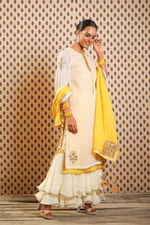 IVORY AND PITAMBARI YELLOW SIGNATURE LAYERED KURTA PAIRED WITH DOUBLE LAYERED SHARARA AND COTTON DUPATTA.