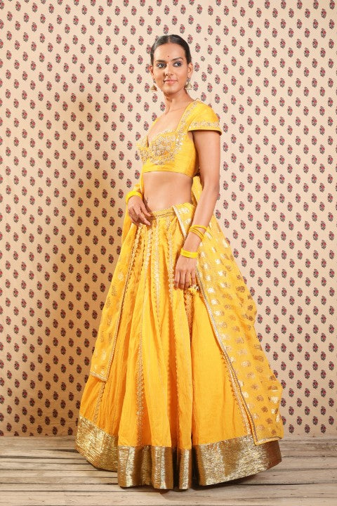 PITAMBARI YELLOW COTTON SILK BLOUSE PAIRED WITH ORGANDI LEHENGA AND KOTA DORIA DUPATTA.