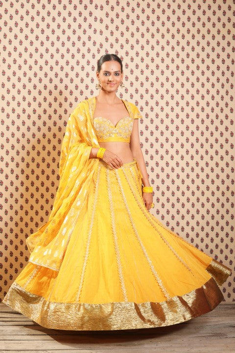 PITAMBARI YELLOW COTTON SILK BLOUSE PAIRED WITH ORGANDI LEHENGA AND KOTA DORIA DUPATTA.