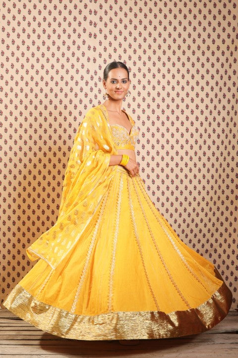 PITAMBARI YELLOW COTTON SILK BLOUSE PAIRED WITH ORGANDI LEHENGA AND KOTA DORIA DUPATTA.