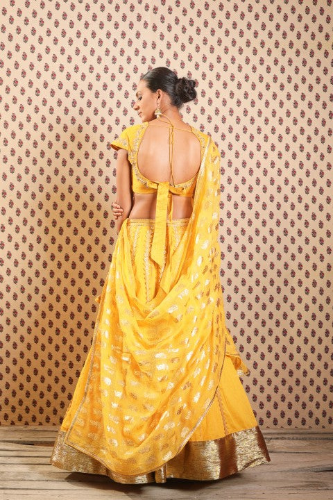 PITAMBARI YELLOW COTTON SILK BLOUSE PAIRED WITH ORGANDI LEHENGA AND KOTA DORIA DUPATTA.