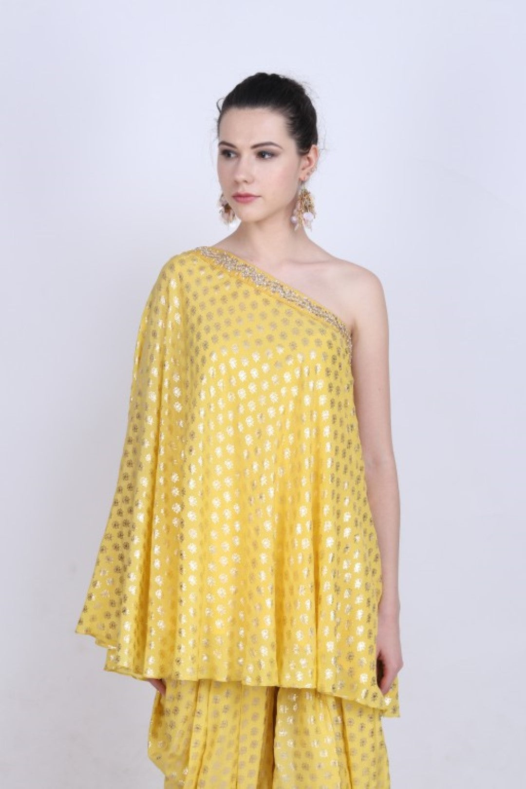 Pitambari yellow crepe gold foil printed one  shoulder top with kundan jaal embroidery and paired with a gold foil printed cowl dhoti