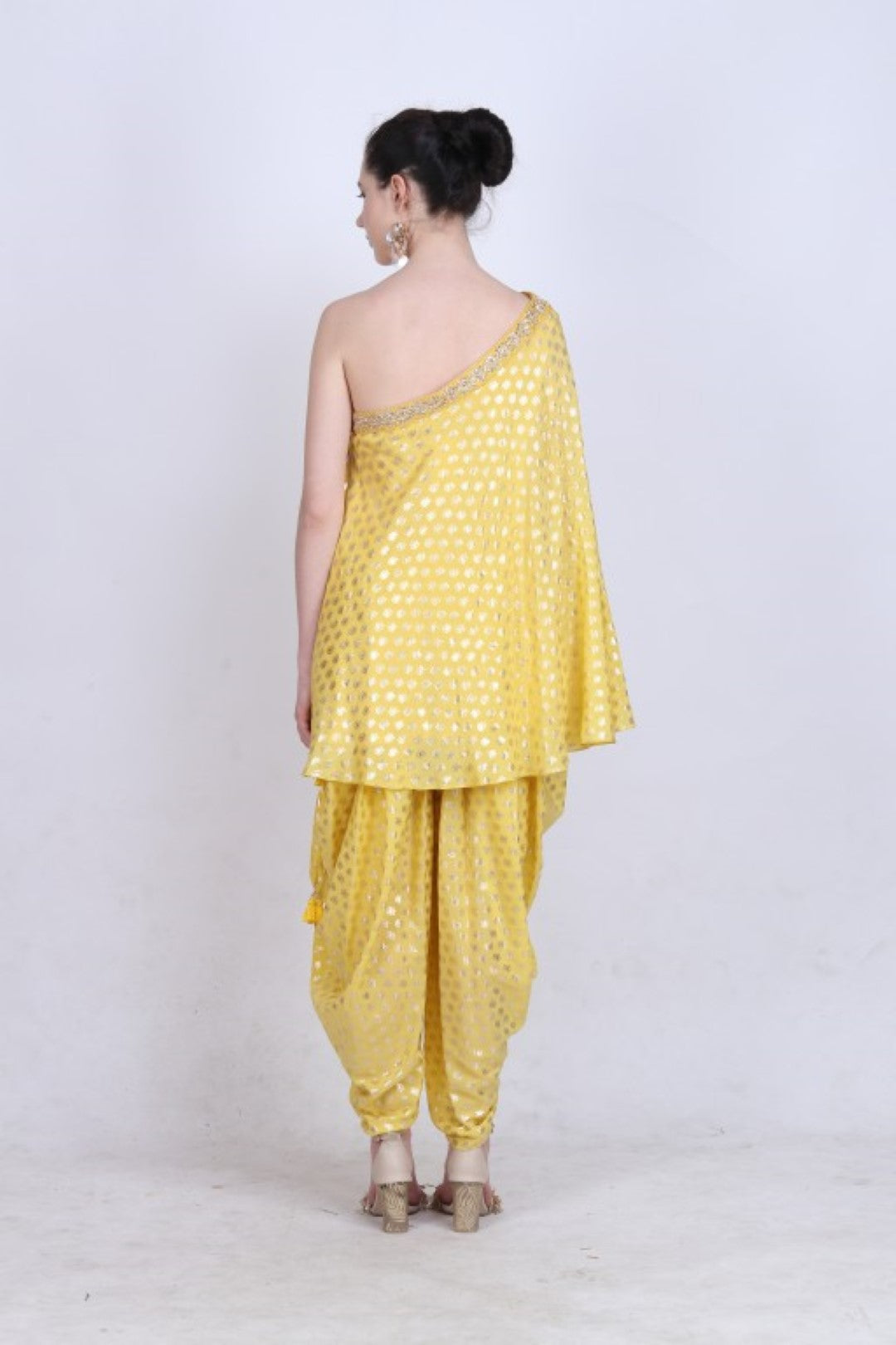 Pitambari yellow crepe gold foil printed one  shoulder top with kundan jaal embroidery and paired with a gold foil printed cowl dhoti