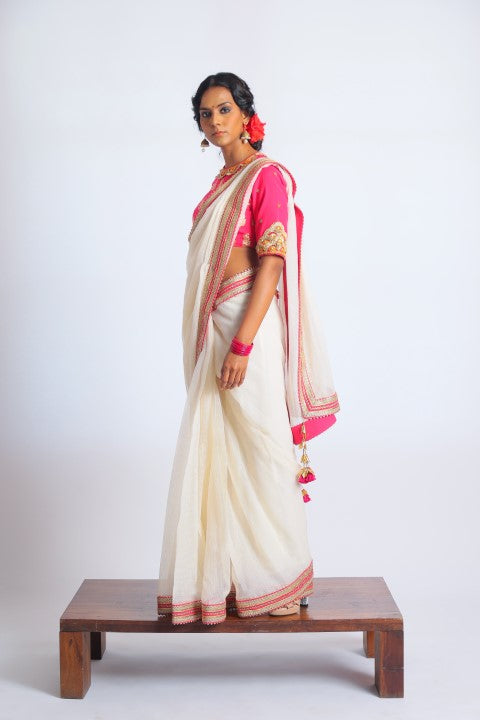 IVORY HANDWOVEN KOTA DORIA SAREE PAIRED WITH FUSCHIA PINK SIGNATURE MUGHAL BUTA PRINT BLOUSE.