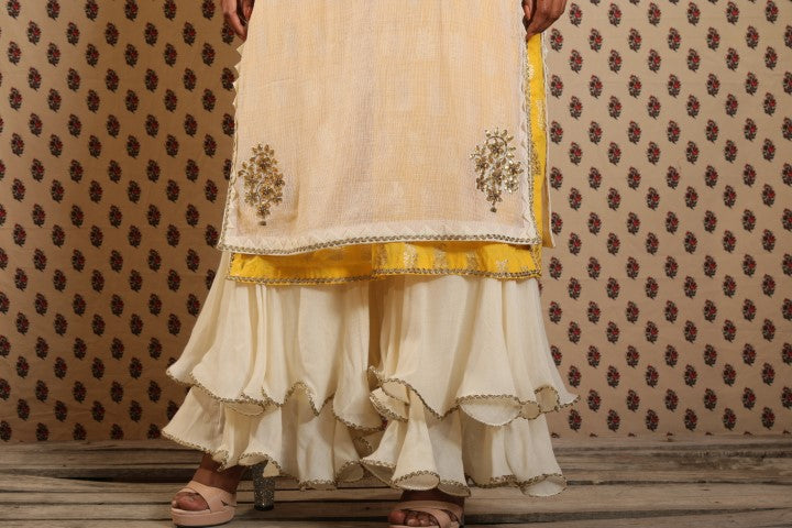 IVORY AND PITAMBARI YELLOW SIGNATURE LAYERED KURTA PAIRED WITH DOUBLE LAYERED SHARARA AND COTTON DUPATTA.