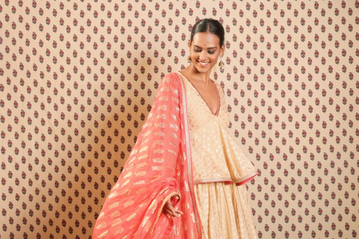 LIGHT CAMEL PEPLUM BLOUSE PAIRED WITH LOTUS PRINT LEHENGA DUPATTA.